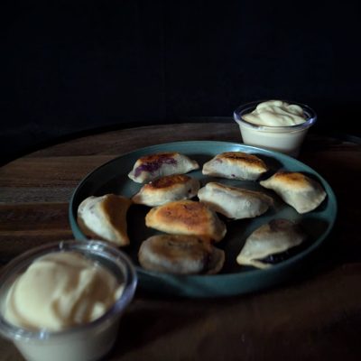 A homemade dessert pierogi, freshly taken from the freezer, served with a creamy cream cheese dip for a sweet and indulgent treat.