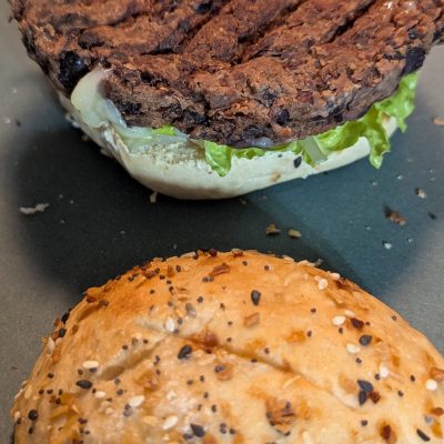 Black Bean Burger with Everything Bagel Bun & Creamy Garlic Aioli A hearty black bean burger on a soft bun sprinkled with everything bagel seasoning, topped with crisp lettuce and a drizzle of creamy garlic aioli.